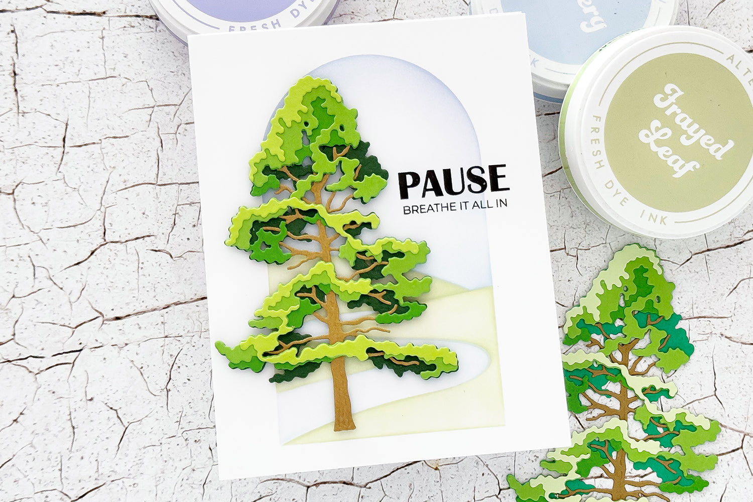 Scenic handmade card featuring the Altenew Jack Pine Tree Layering Die Set with ink blending, masking, rolling hills, and a peaceful landscape background.